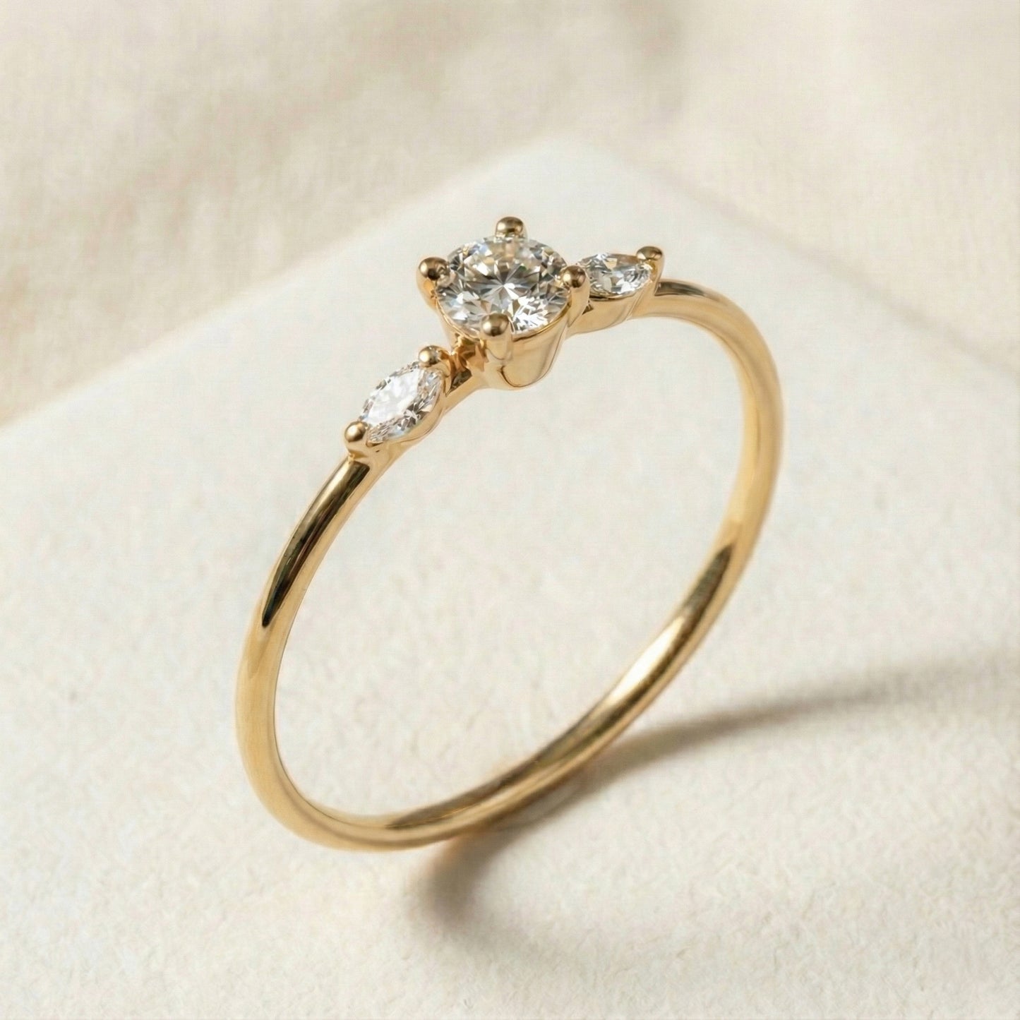 Handcrafted 14K gold three-stone diamond ring featuring a raised round center diamond and two marquise side stones creating a wing-like silhouette. Slim polished band, modern and elegant design ideal for engagement or everyday luxury wear.