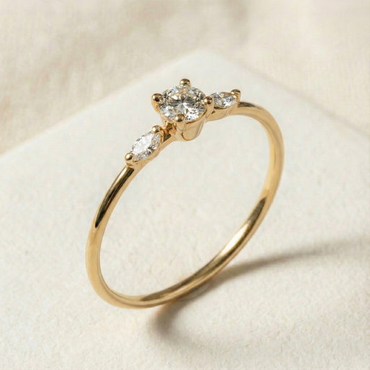 Handcrafted 14K gold three-stone diamond ring featuring a raised round center diamond and two marquise side stones creating a wing-like silhouette. Slim polished band, modern and elegant design ideal for engagement or everyday luxury wear.