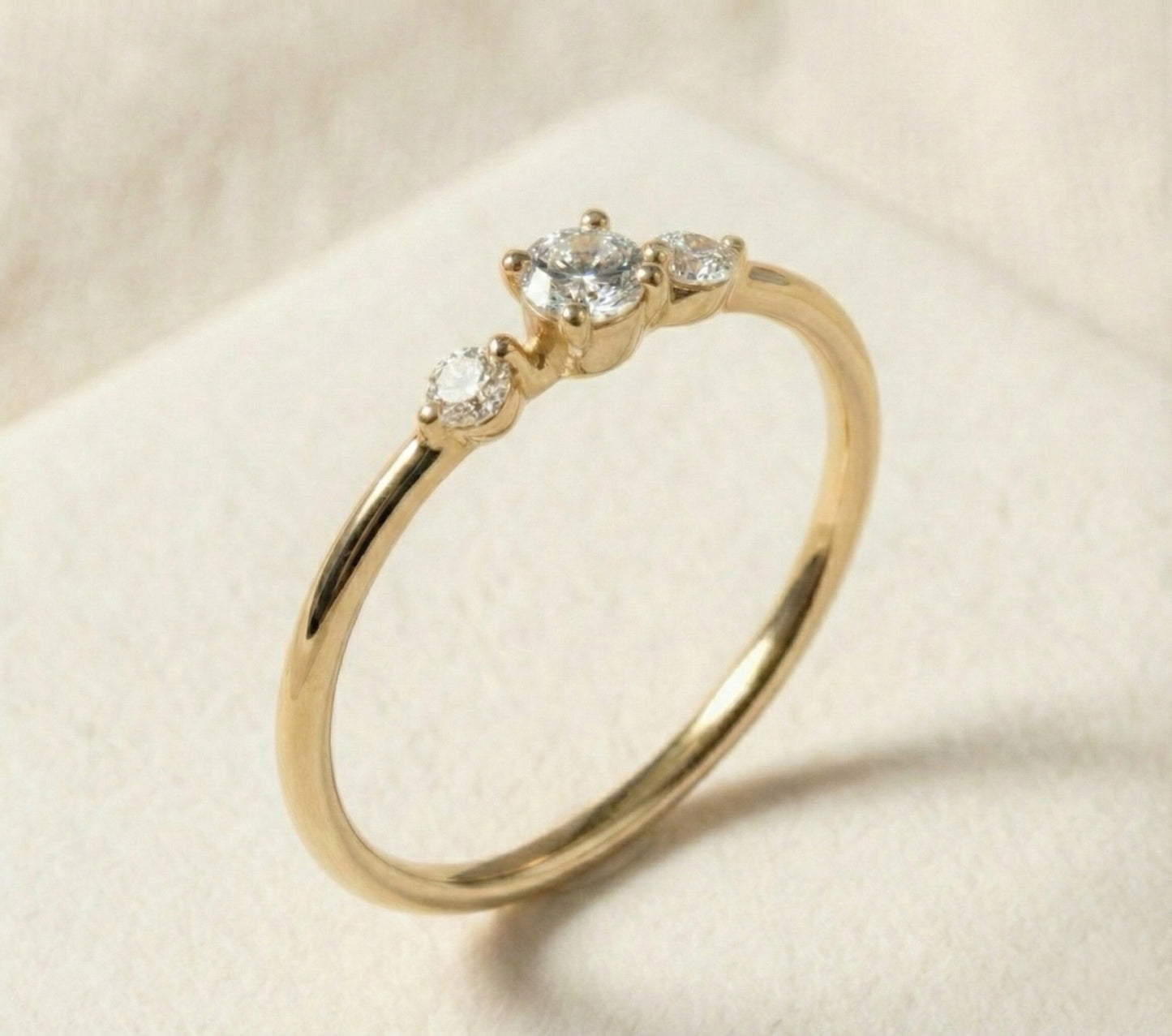 Handcrafted 14k gold three-stone diamond ring featuring a brilliant round center stone with two smaller side diamonds. Minimalist, modern design with a slim polished band, ideal for engagement or fine jewelry.