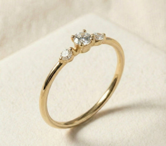 Handcrafted 14k gold three-stone diamond ring featuring a brilliant round center stone with two smaller side diamonds. Minimalist, modern design with a slim polished band, ideal for engagement or fine jewelry.